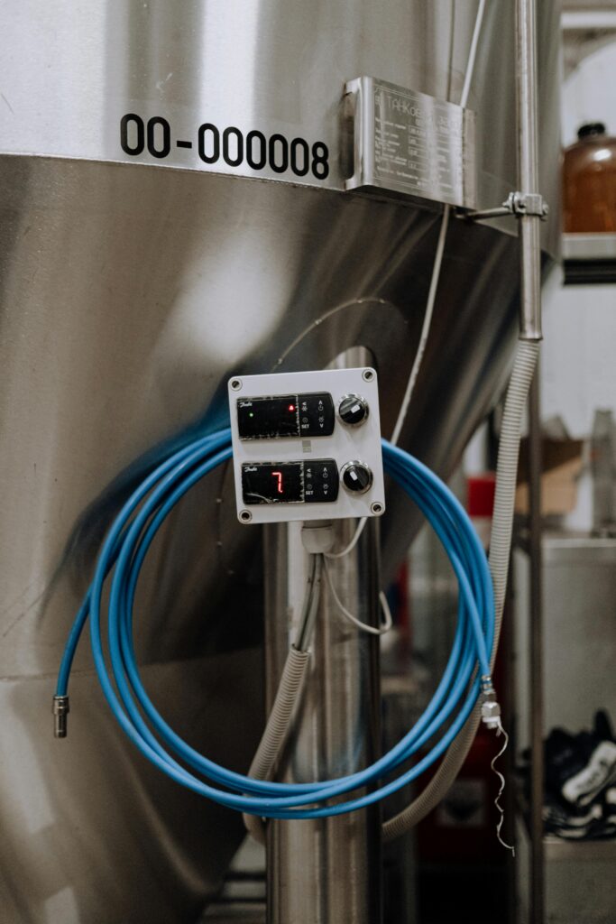 pexels photo 5532839 5532839 Close-up of a stainless steel manufacturing tank with digital display and hose in an industrial setting.